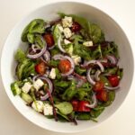 Ensalada mediterránea fresca con verduras, olivas y feta sobre una mesa.